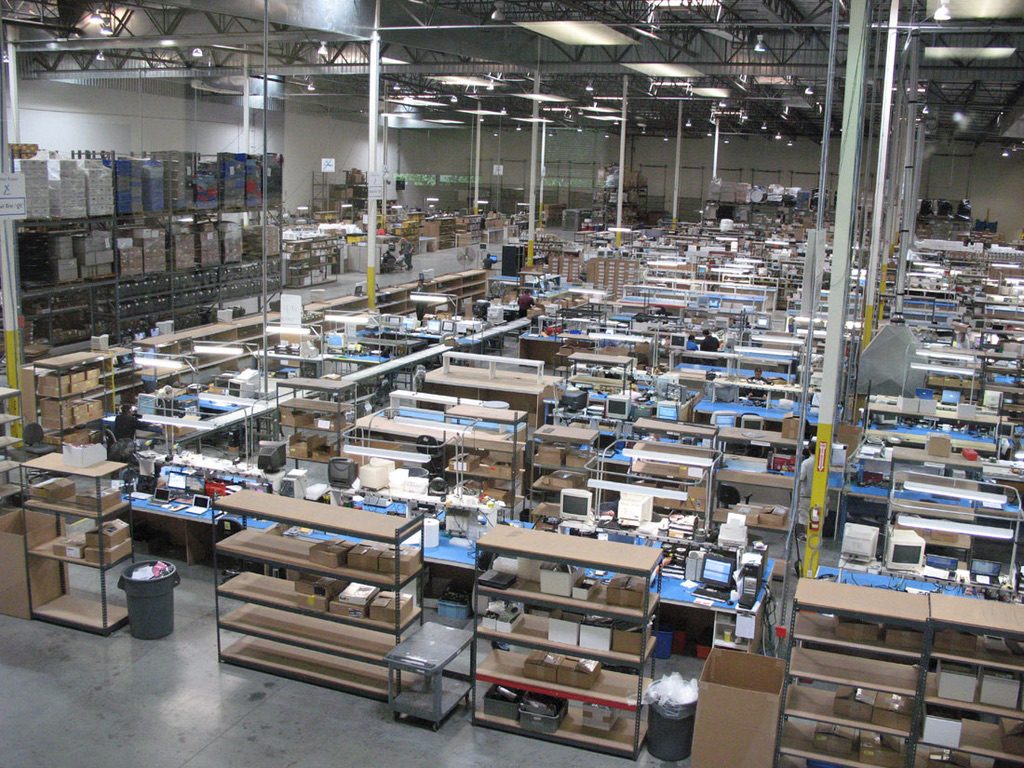 Wide view of the Computer Parts Unlimited operations floor with rows of parts shelving and workstations
