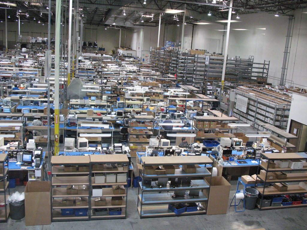 Second view of the Computer Parts Unlimited warehouse floor showing parts inventory, packing stations and shelving